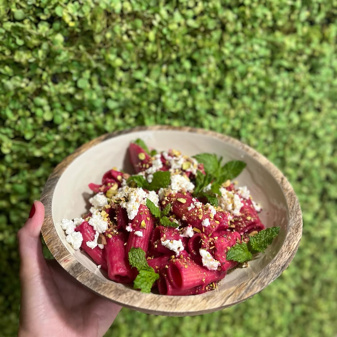 Salada de beterraba com queijo feta e folhas verdes, sobre prato de madeira
